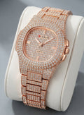 A luxury rose gold watch encrusted with diamonds, displayed on a white cylindrical stand against a gray background.