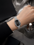 RELO minimalist oval silver watch with black dial and metal chain strap worn on wrist.